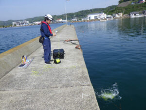 スタッフが海岸調査で水中ドローンを操作しています。